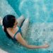 Aerial view of a woman in a blue swimsuit lounging in a swimming pool, capturing a serene moment.